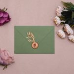 green envelope with gold stamp and flowers around it