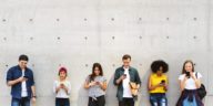 a group of young adults outdoors using smartphones