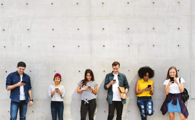 a group of young adults outdoors using smartphones