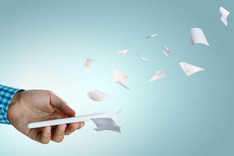 hand holding smartphone with book pages coming out of it