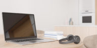 a laptop, headphones and books on a table in someone's home