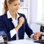 woman using a calculator at a desk with binders on it