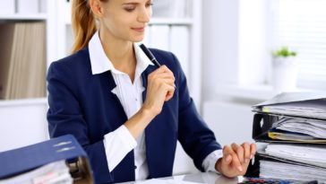 woman using a calculator at a desk with binders on it