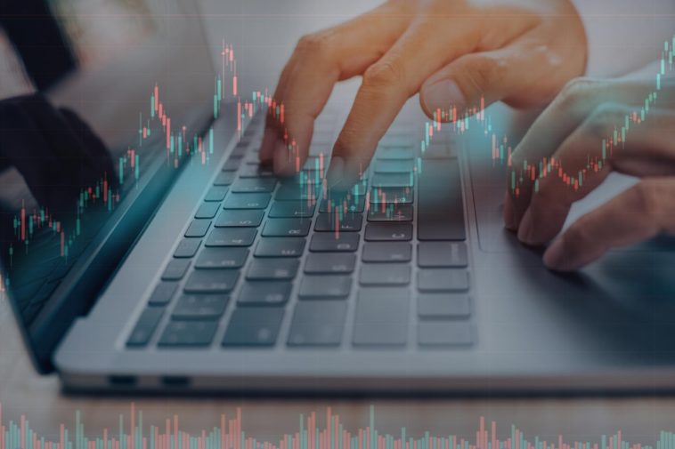 closeup of hands typing on a laptop and a 3d chart