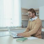 man with headphones working from home using a laptop