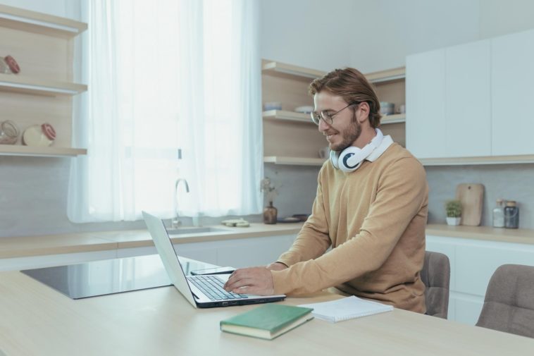 man with headphones working from home using a laptop