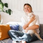 woman sitting on a couch holding a cat