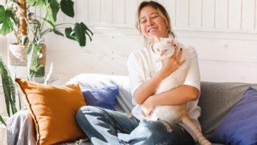 woman sitting on a couch holding a cat