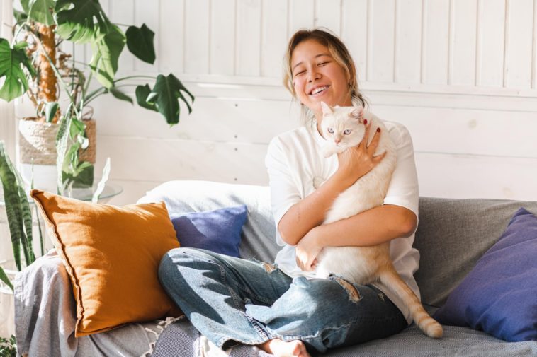 woman sitting on a couch holding a cat