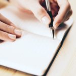 female hands writing with pen in a notebook