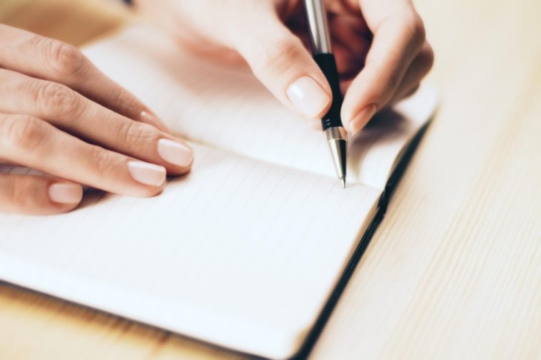 female hands writing with pen in a notebook