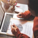 woman working at a laptop and looking at a business report