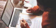 woman working at a laptop and looking at a business report