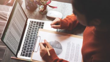 woman working at a laptop and looking at a business report