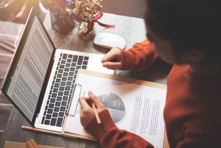 woman working at a laptop and looking at a business report