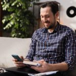 man holding a smartphone and a book