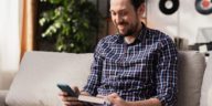 man holding a smartphone and a book