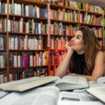 woman sitting in a library surrounded by books