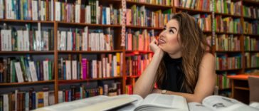 woman sitting in a library surrounded by books