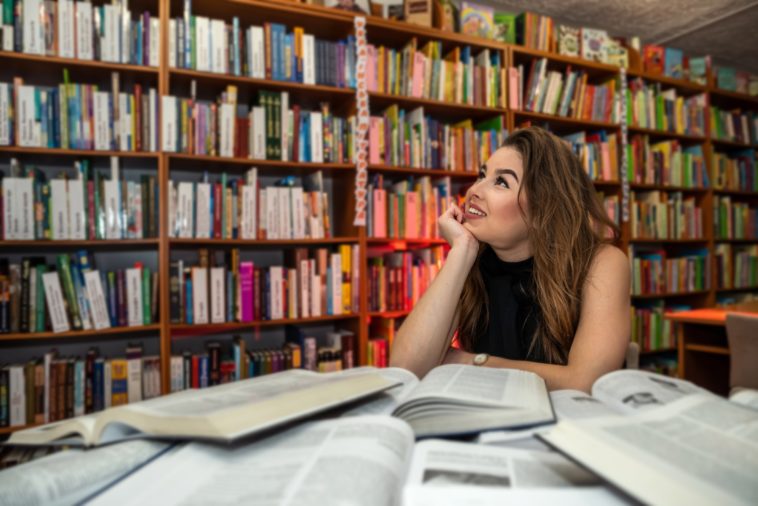 woman sitting in a library surrounded by books