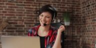 smiling woman with a headset working on a laptop from home