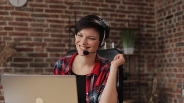 smiling woman with a headset working on a laptop from home