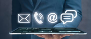 businessman holding a tablet with 3D mail, phone, email and chat icons above it