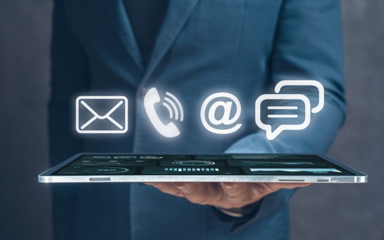 businessman holding a tablet with 3D mail, phone, email and chat icons above it