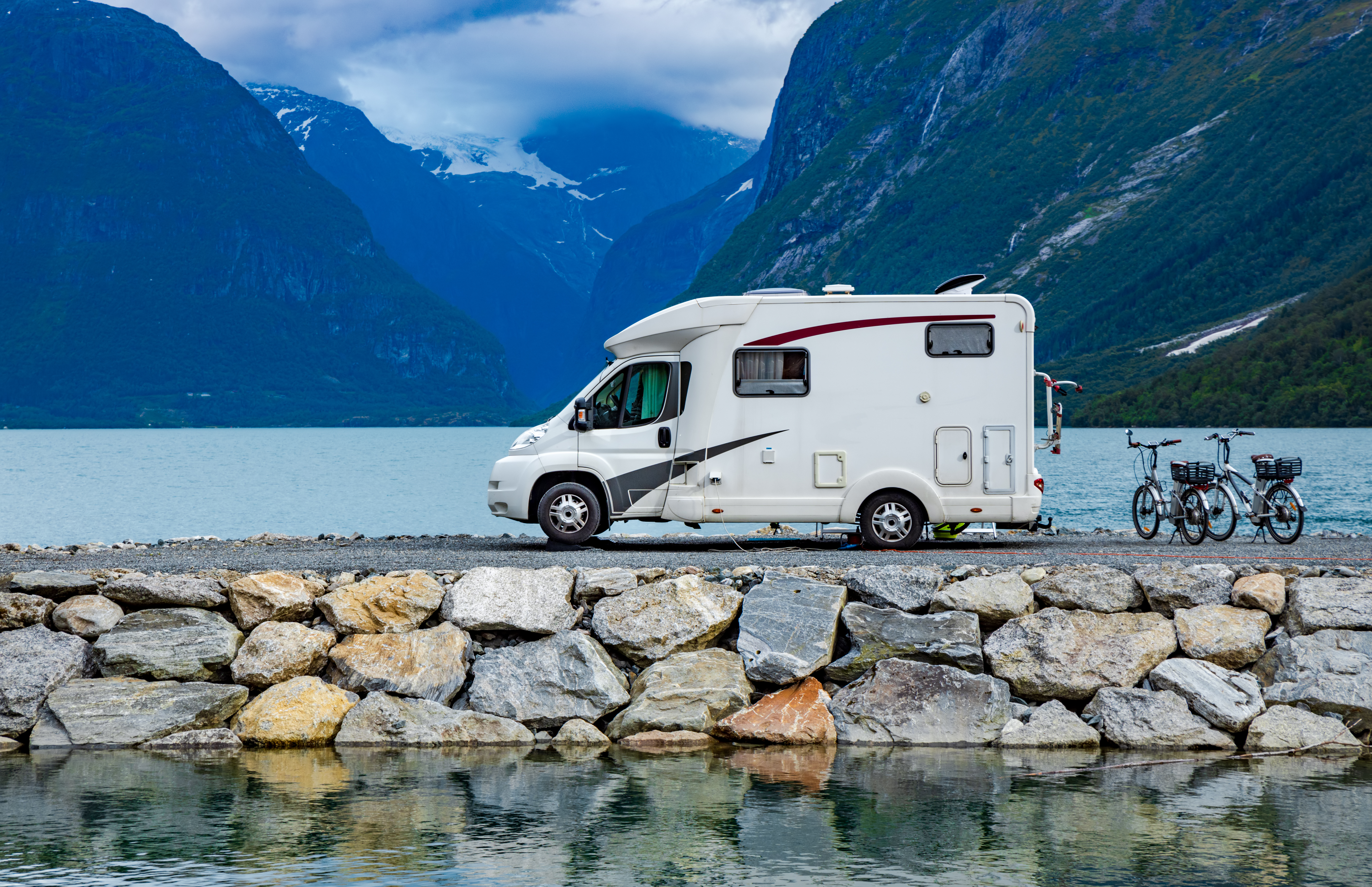 white RV on a stone bridge next to a lake