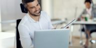 smiling man with headphones using laptop while on a call