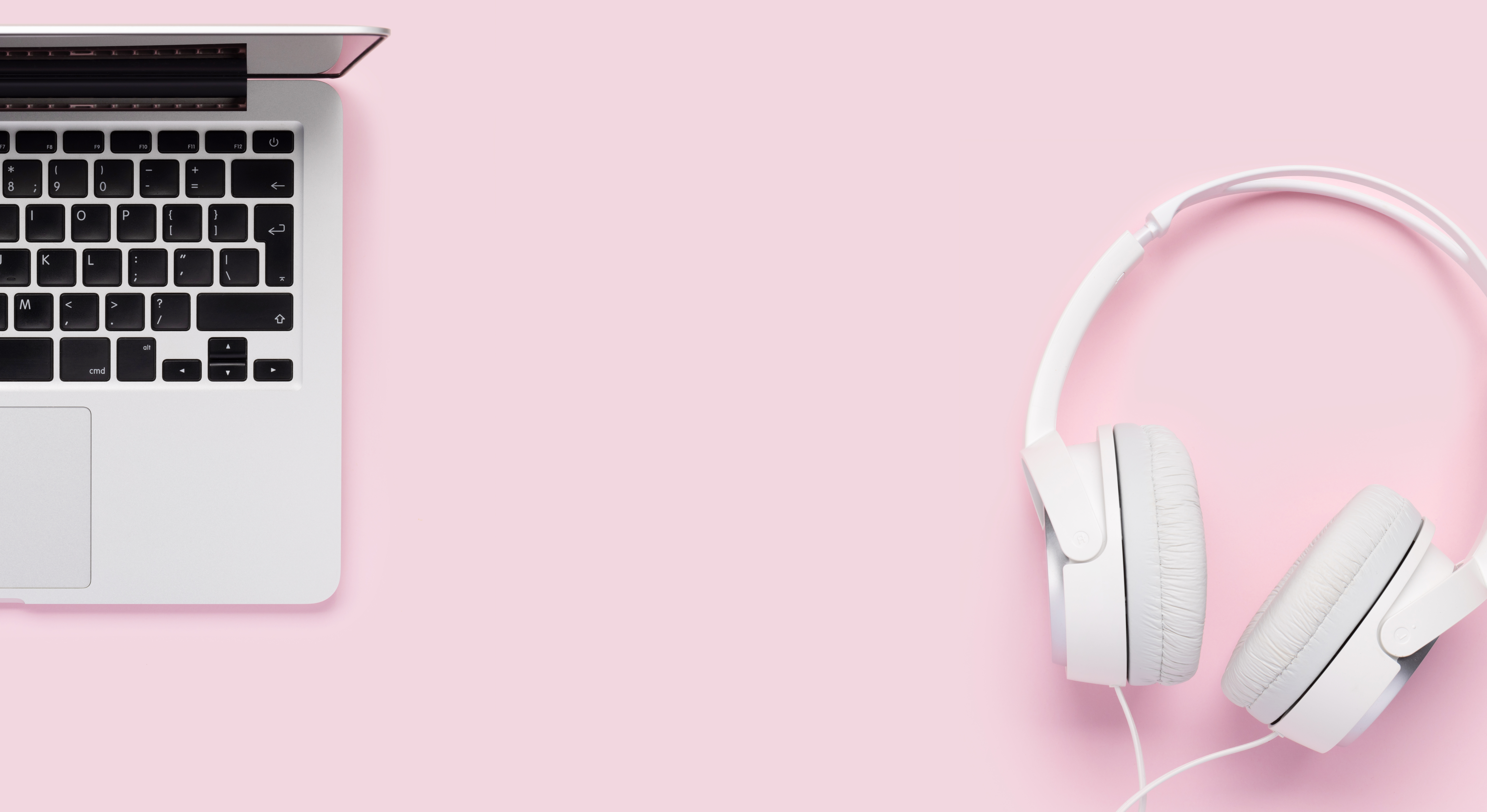 white laptop and headphones on a pink surface