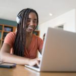 woman with headphones working on a laptop from home