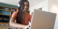 woman with headphones working on a laptop from home