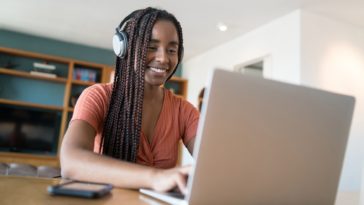 woman with headphones working on a laptop from home