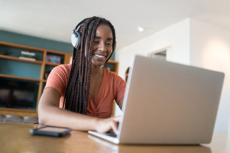 woman with headphones working on a laptop from home