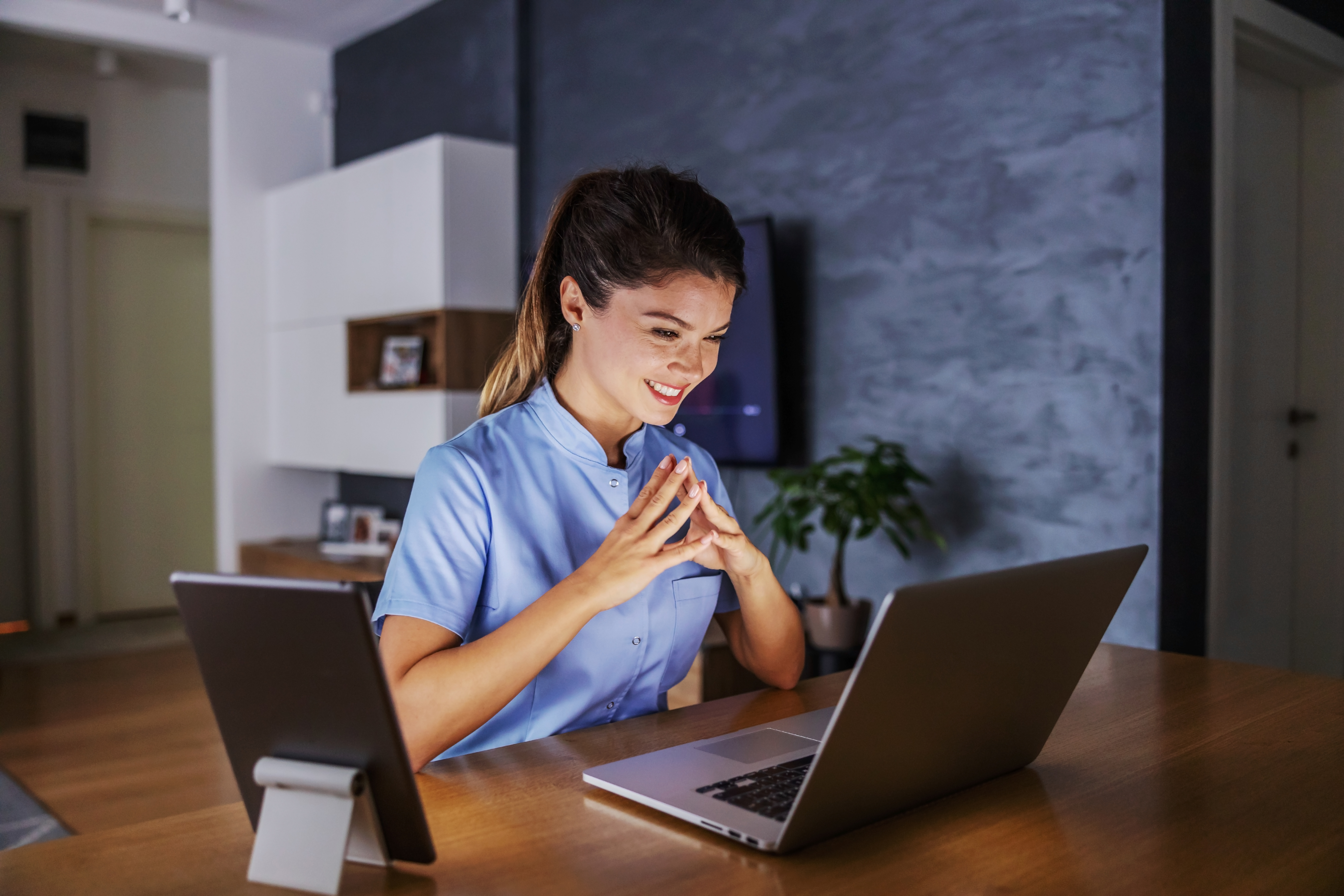 smiling woman sitting at home looking at a laptop