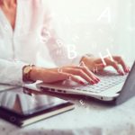 woman working on a laptop with 3D letters coming out of it