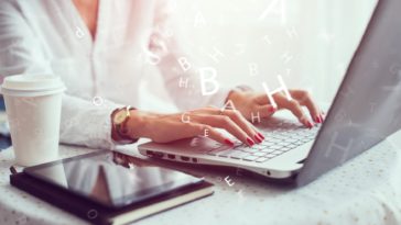 woman working on a laptop with 3D letters coming out of it