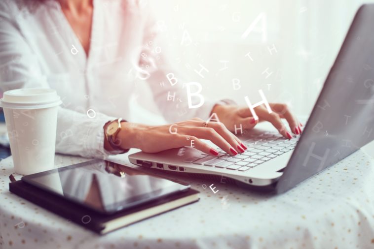 woman working on a laptop with 3D letters coming out of it