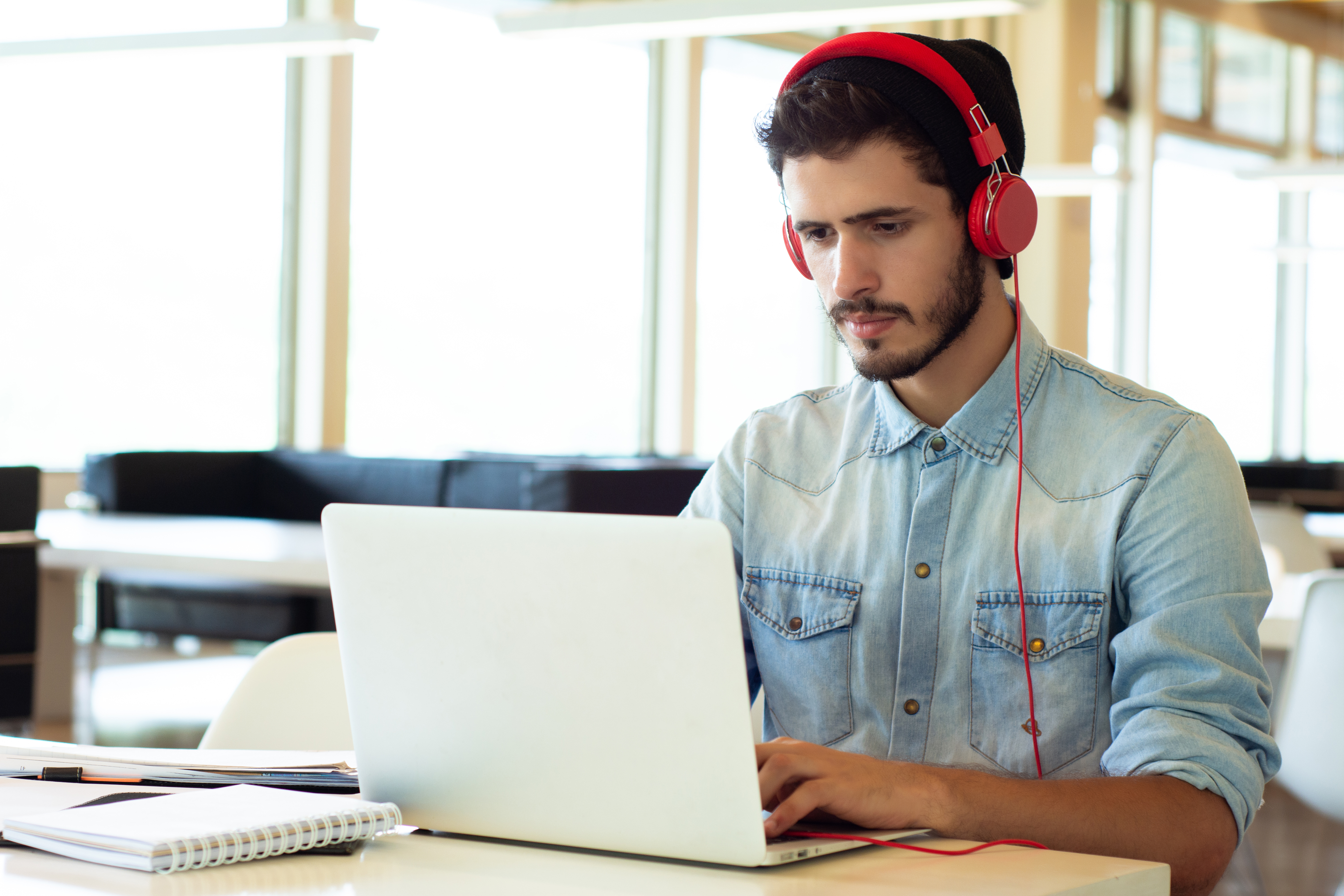 man with red headphones typing on a laptop