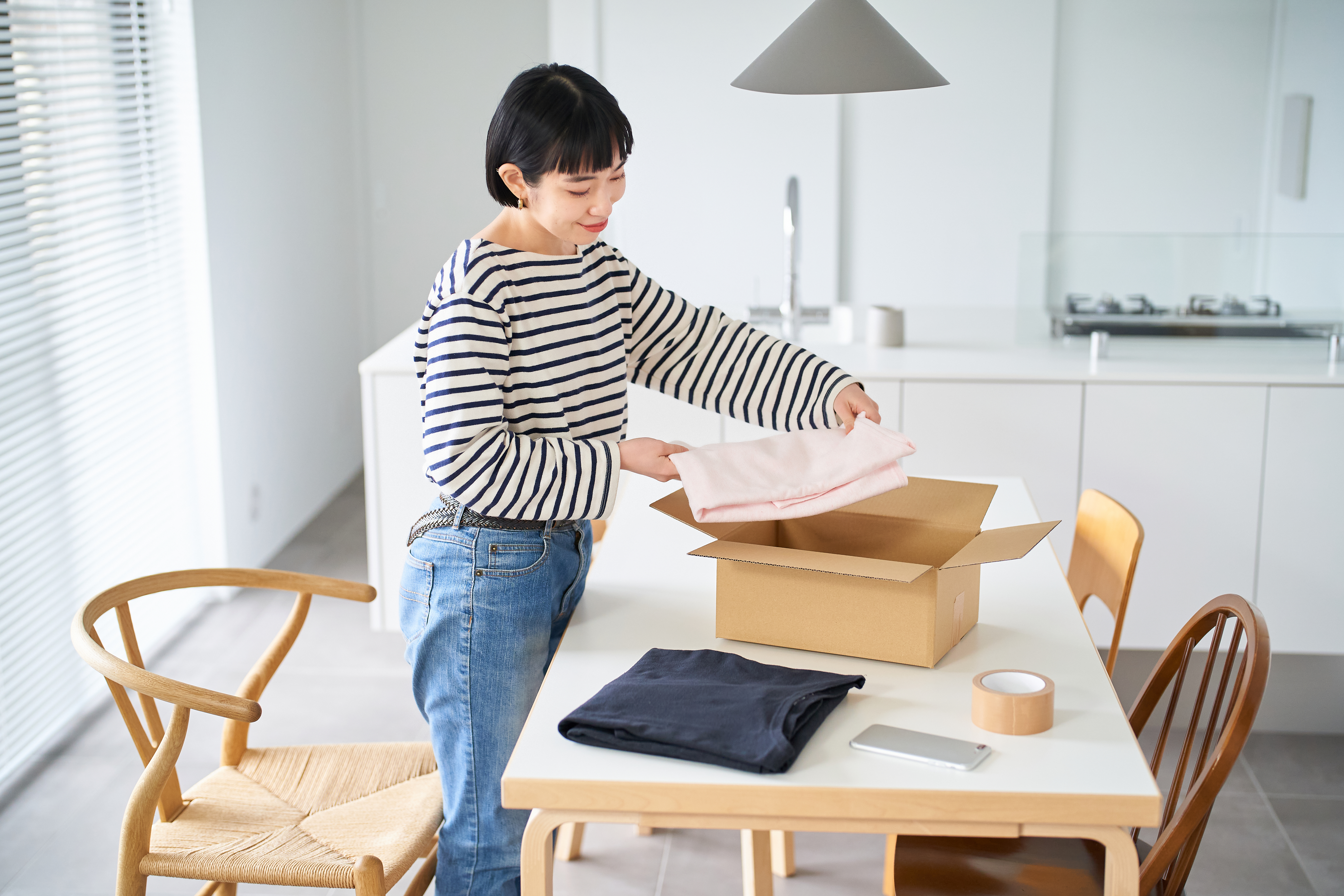 woman packing clothes into a cardboard box
