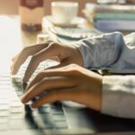 hands typing on a laptop in a home office