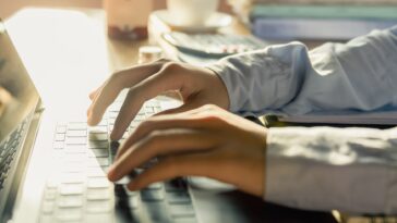 hands typing on a laptop in a home office