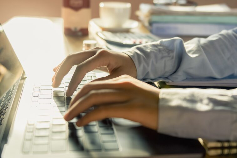 hands typing on a laptop in a home office