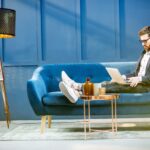 man sitting on a couch and working on a laptop