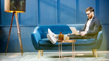 man sitting on a couch and working on a laptop