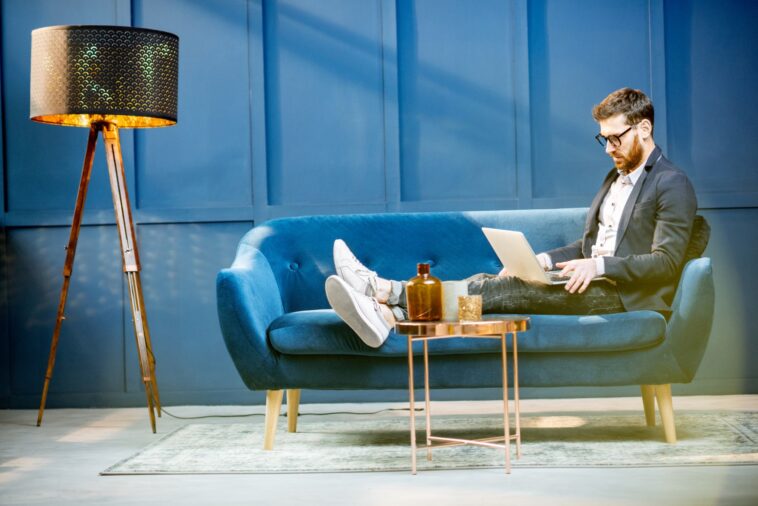 man sitting on a couch and working on a laptop