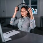 woman sitting at a desk with a computer putting on a headset