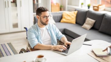 man in a wheelchair working on a laptop from home