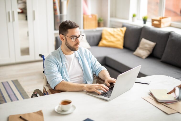 man in a wheelchair working on a laptop from home